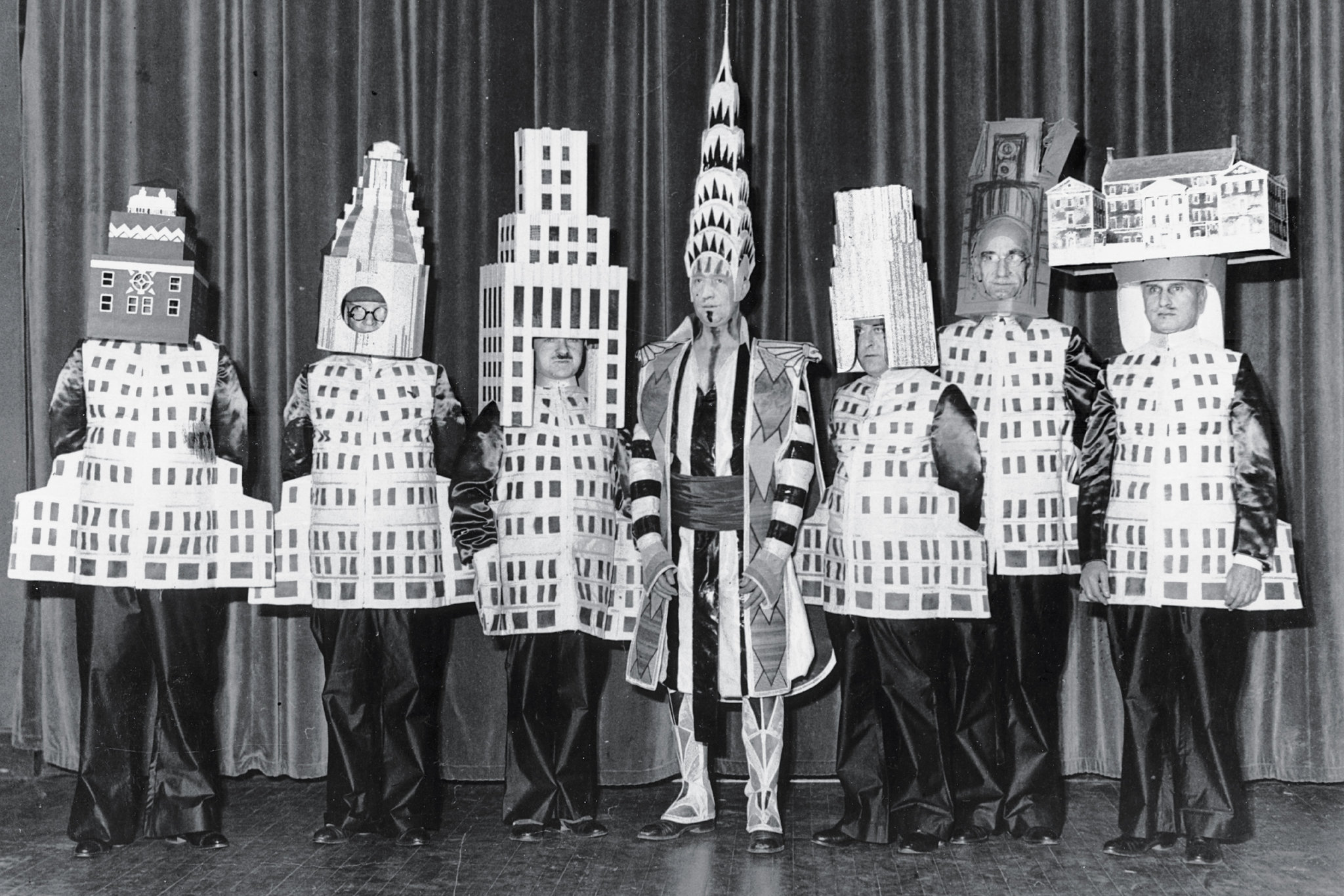 Больше двадцати архитекторов пришли на нью-йоркский Бал изящных искусств 1931 года в костюмах зданий, которые они сами спроектировали. Слева направо: Стюарт Уокер в костюме Фуллеровского небоскреба, Леонард Шульце, одетый в отель «Уолдорф-Астория», Эли Жак Кан в образе небоскреба корпорации «Сквибб», Уильям ван Ален в костюме Крайслер-билдинг, Даниэль Уэйд в башне «Метрополитен-Лайф», Ральф Уокер в макете Уолл-стрит-билдинг и Джозеф Фридлэндер, наряженный в Нью-Йоркский городской музей.