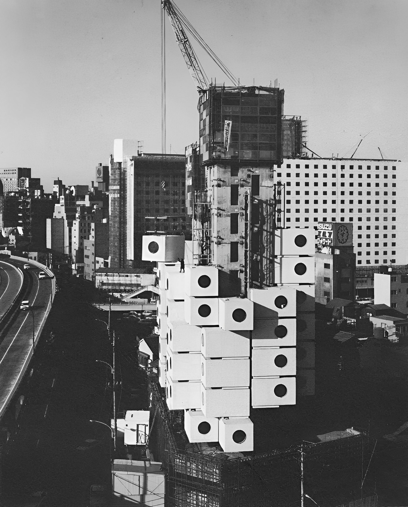 (9) Nakagin Capsule Tower, Tokyo 1972, suspends 140 rooms from two concrete cores. These steel boxes are modified shipping containers which were prefabricated in Osaka, trucked to Tokyo and lifted into place by a crane. They include every amenity which one could miniaturize and put into one room, except a stove. (The tower is in the restaurant district.)