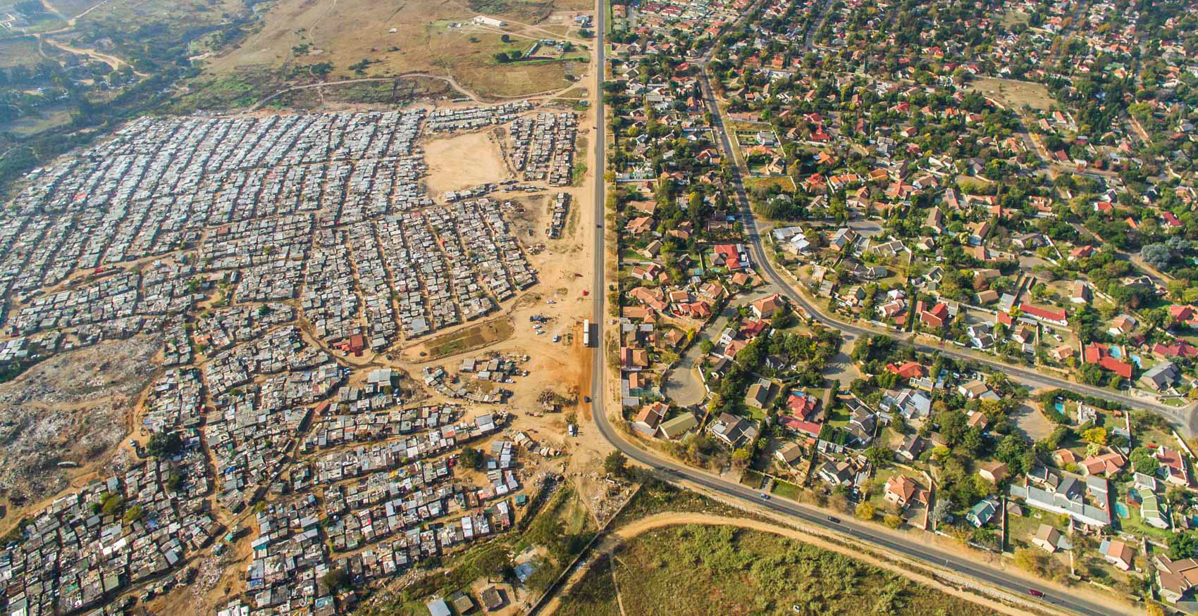 бидонвиль Kya Sands (слева) и пригород Bloubosrand (справа) в Йоханнесбурге, ЮАР