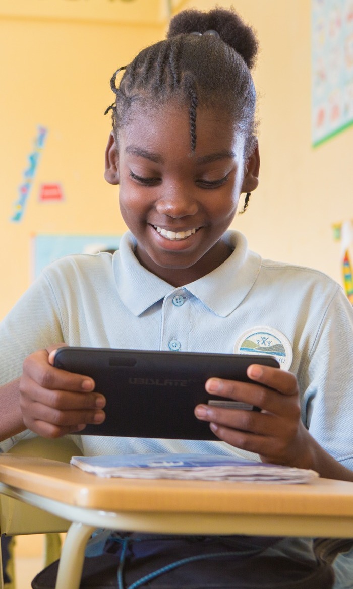 гаитянская школьница читает книгу на планшете