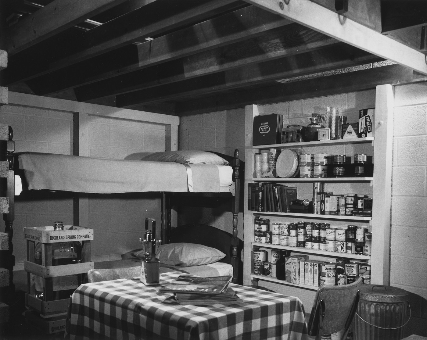 Интерьер семейного ядерного бомбоубежища, устроенного в подвале дома. В убежище имеется 14-дневный запас продовольствия и воды, радио с батарейным питанием, автономные источники света, набор медикаментов и инструментов. Ориентировочно 1957 год