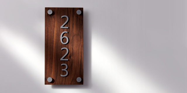 Табличка с номером, изготовленная из древесины грецкого ореха и листа акрилового пластика цвета серебряный металлик.
